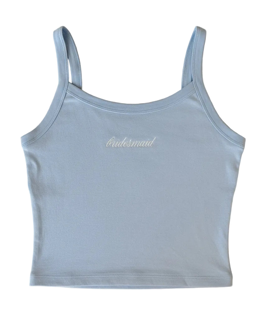 The Bridesmaid Tank: soft blue cropped tank with white 'bridesmaid' script on a beige surface