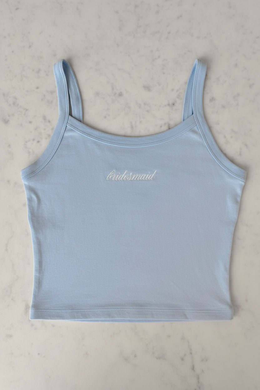 Light blue tank top with 'bridesmaid' text on a beige surface