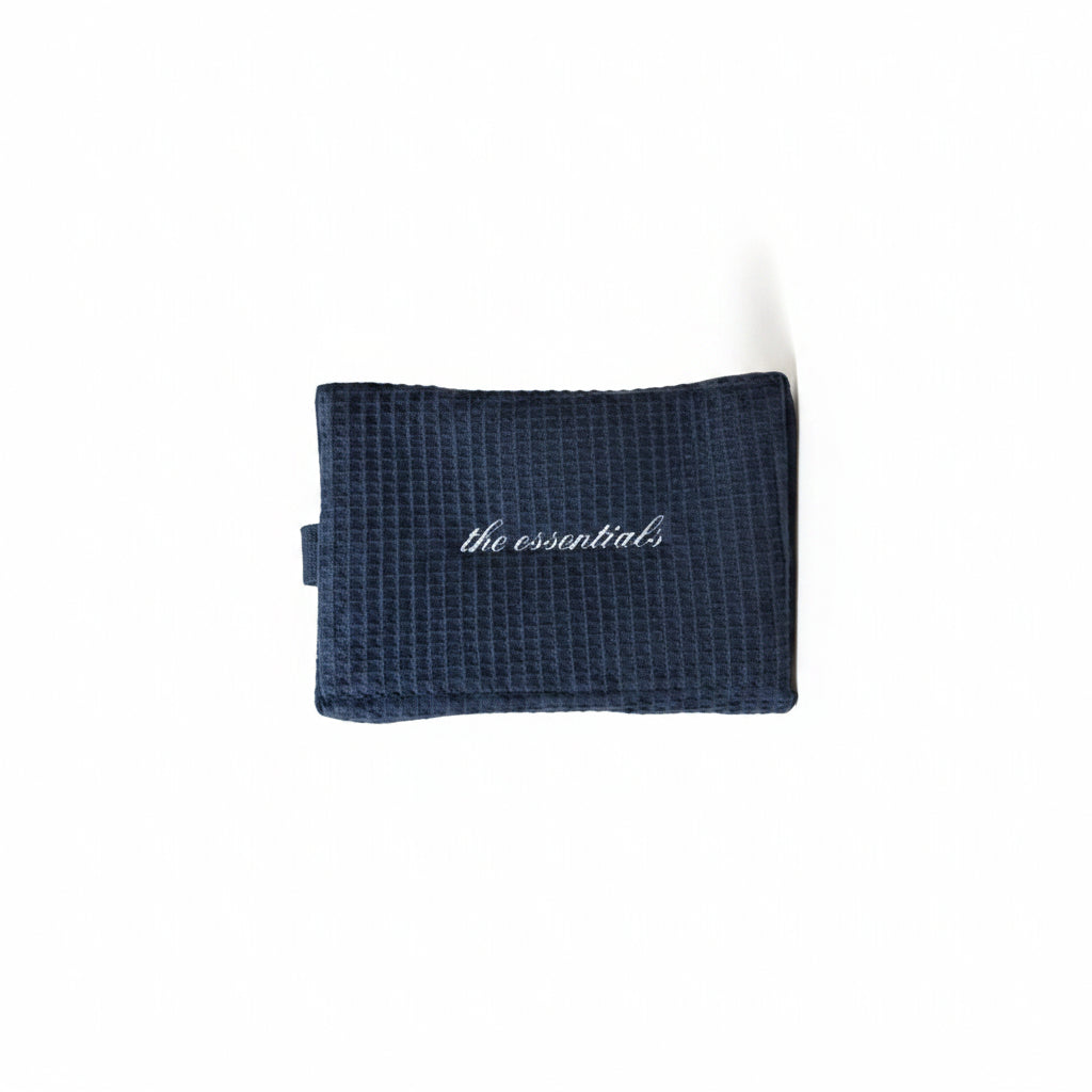 Waffle-textured black pouch with 'the essentials' branding on a light background